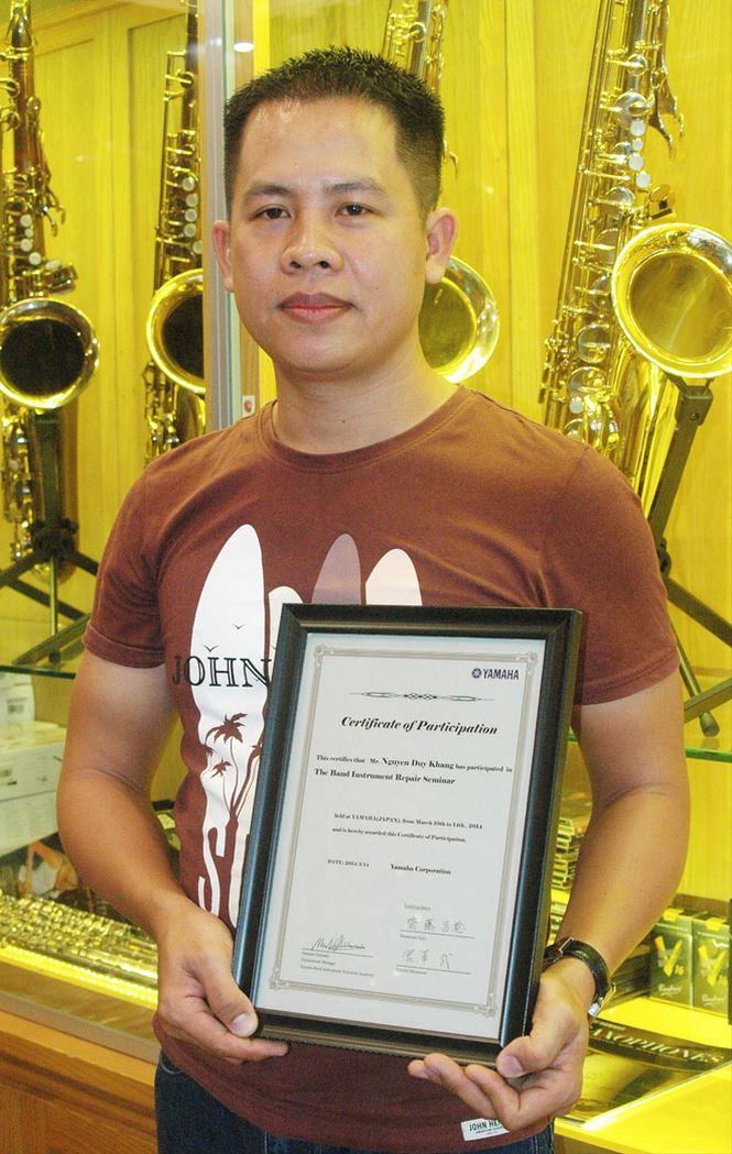 Nghệ nhân Nguyễn Khang với giấy chứng nhận chuyên gia sửa kèn do Nhật Bản cấp. Ảnh: Nguyễn Anh