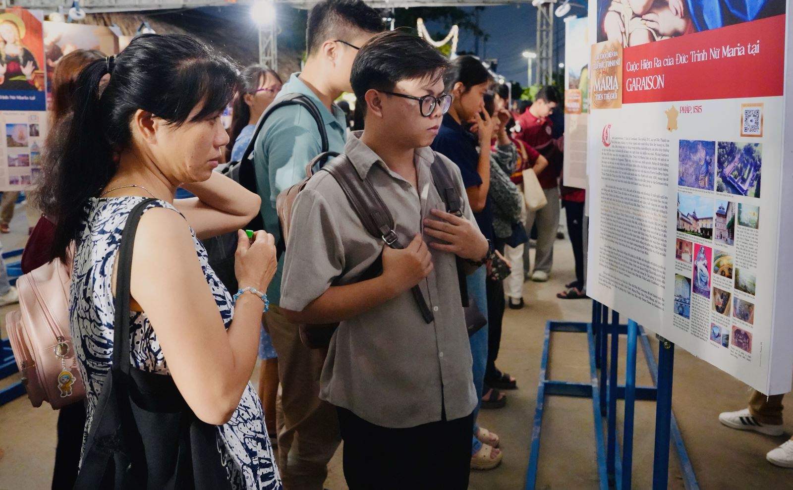 Người tham dự dừng chân tìm hiểu tư liệu và quét mã QR nghe thuyết minh về cuộc hiện ra của Đức Mẹ tại Garaison.